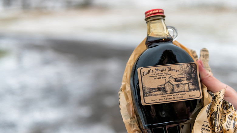 Hand cradling a maple syrup bottle with a tiny handle