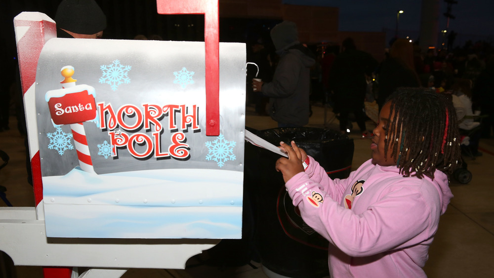 A girl drops a letter to Santa in the special North Pole mailbox before the Christmas tree lighting and grant ceremony at Texas Motor Speedway 