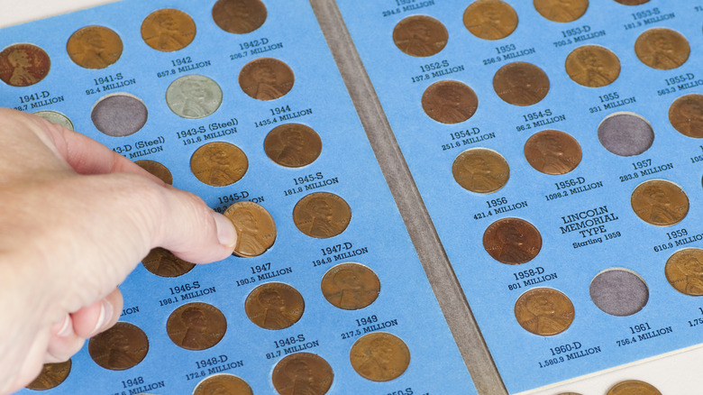 A person adding a penny to a collection book of coins