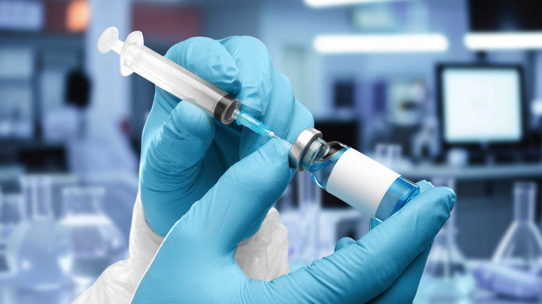 gloved hands with syringe and vaccine