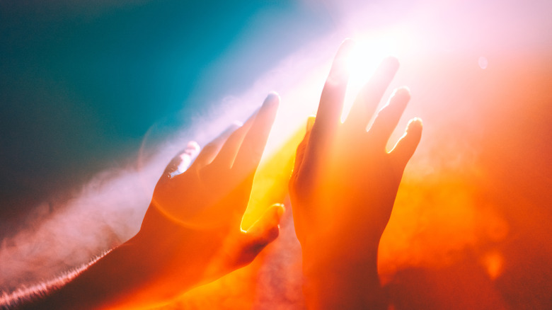 hands reaching into flares of light