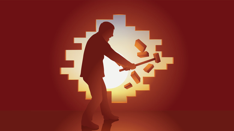 Figure breaking a wall of bricks with a sledgehammer