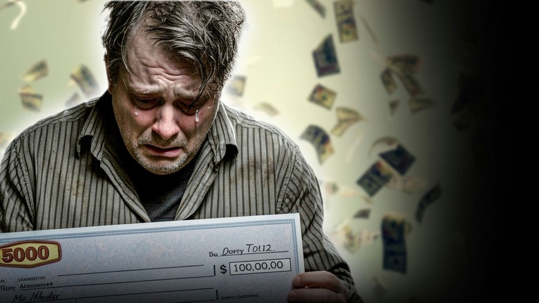 man crying while holding a big check