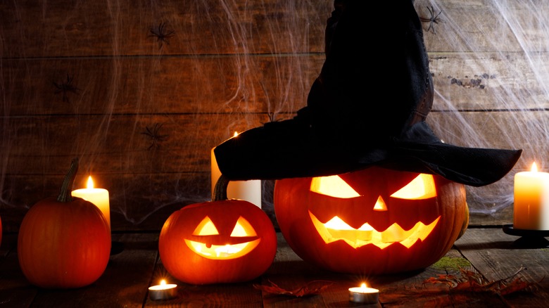 Behatted jack-o'-lantern surrounded by candles