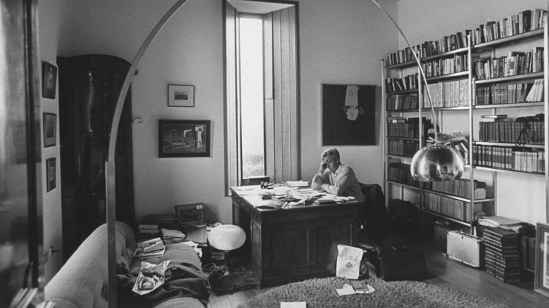 John Le Carre sitting at his desk in front of bookcase