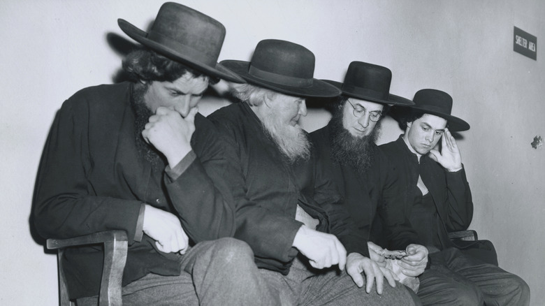 Four Amish men sitting on a bench in a courthouse