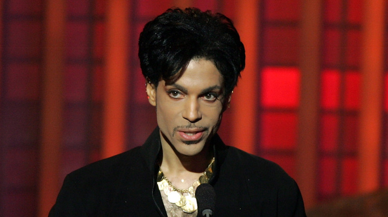 Prince standing at a podium in front of a red background