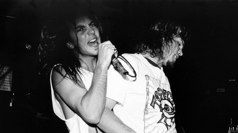 Eddie Vedder singing into mic as Jeff Ament plays bass in performance