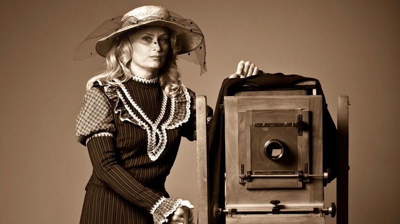 woman standing beside vintage camera