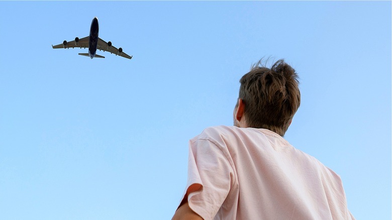 Person looking up at airplane