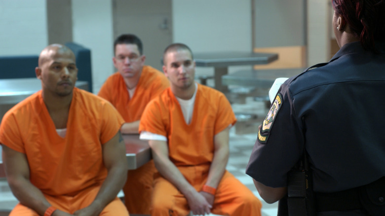 men sitting in jail with officer