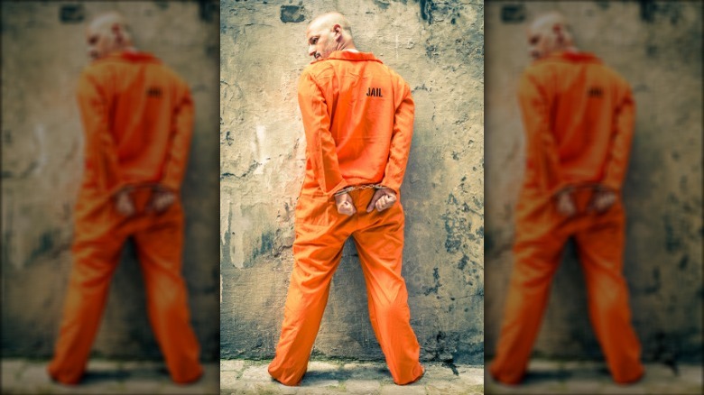 man in orange jail jumpsuit and handcuffs