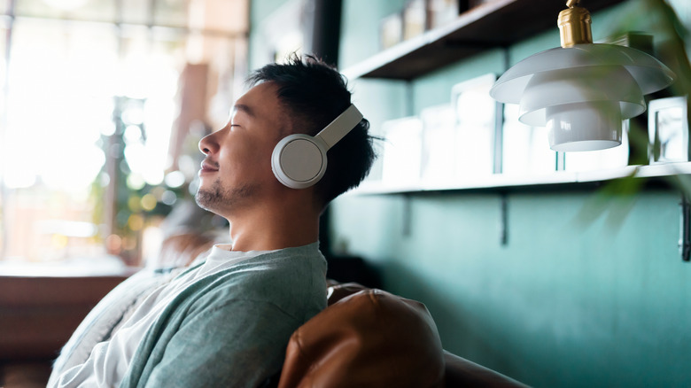 Seated man listening to music through headphones