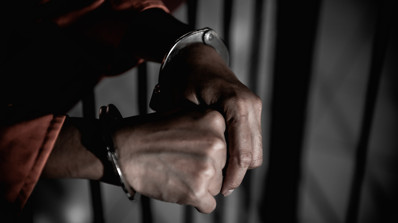 hands in cuffs behind bars