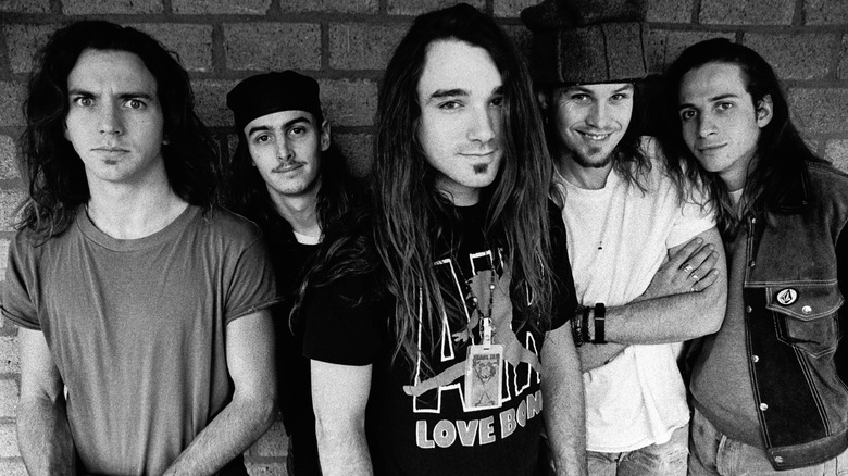 A black and white photo of members of Pearl Jam standing together in front of a brick wall