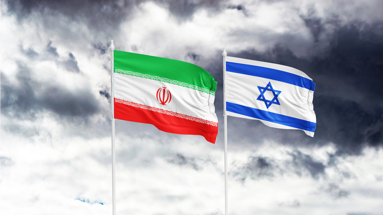 iranian and israeli flags in front of foreboding background