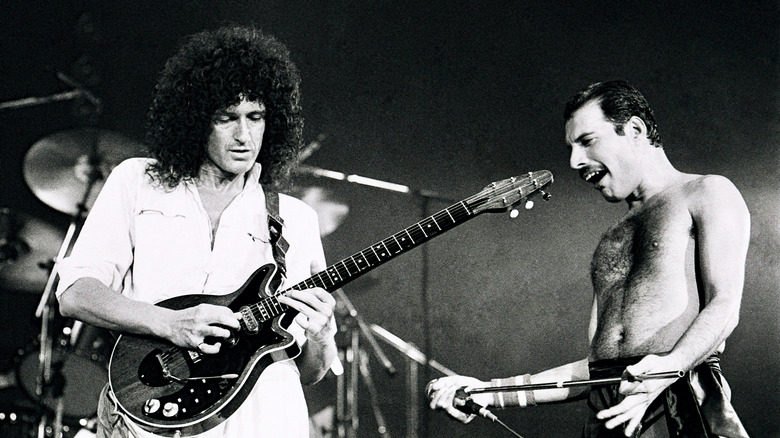 Brian May playing a guitar solo while Freddie Mercury watches