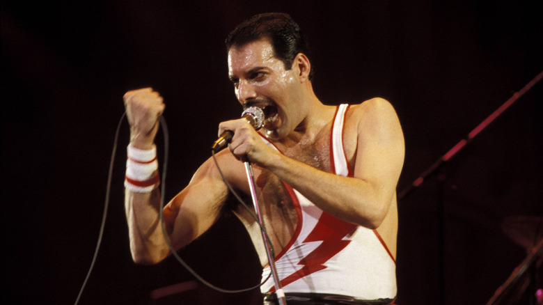 Freddie Mercury singing into a microphone while performing onstage