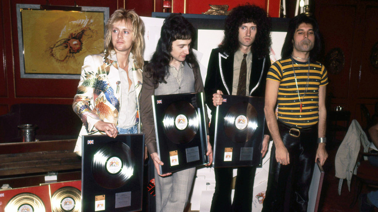 Members of Queen displaying several gold records