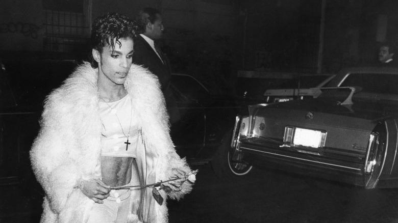 Prince wearing a white faux fur over a belly shirt