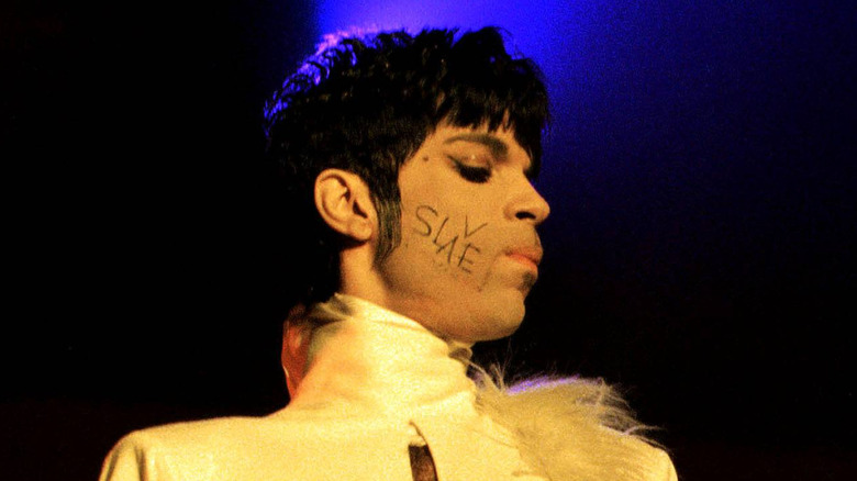 Prince performing in concert with the word Slave written on his cheek