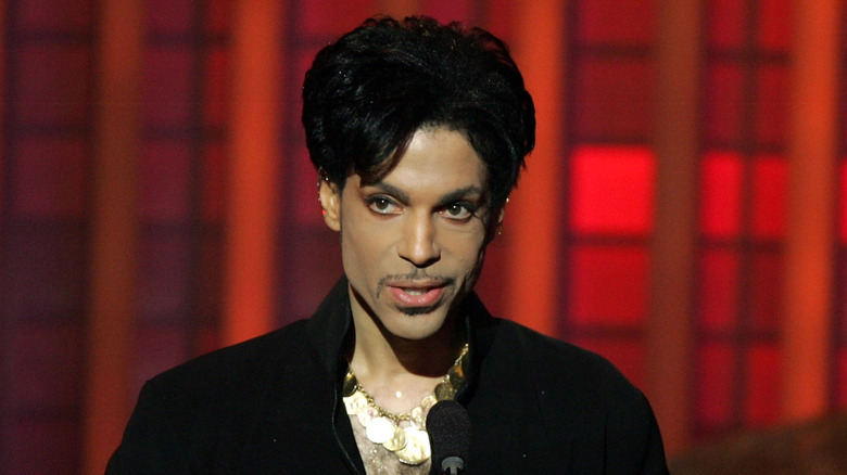 Prince standing at a podium in front of a red background