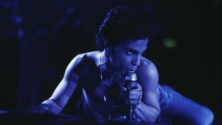 Prince bathed in blue light while horizontal onstage