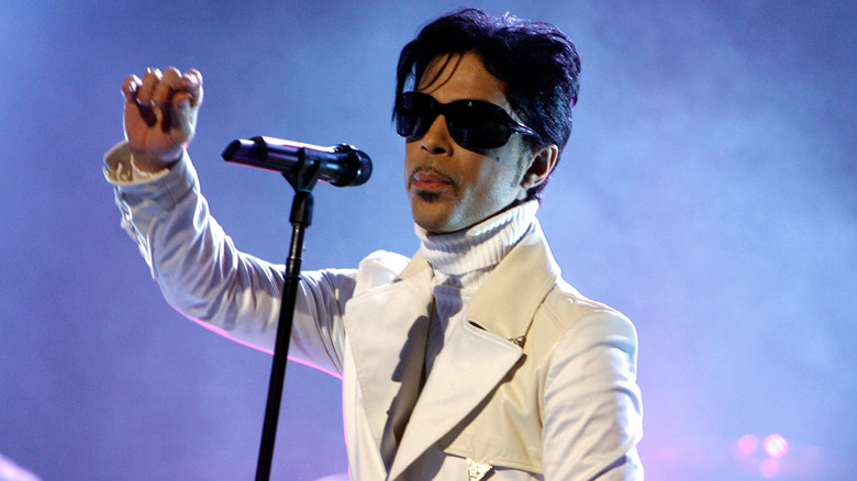 Prince wearing large sunglasses and a white suit in concert