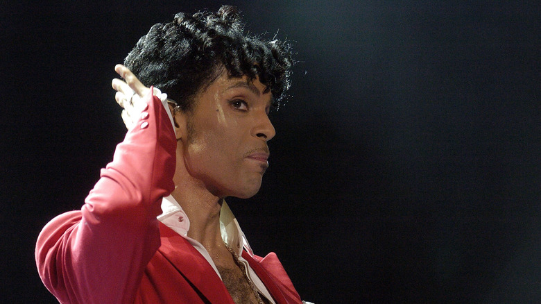 Prince cupping his hand to his ear during a concert