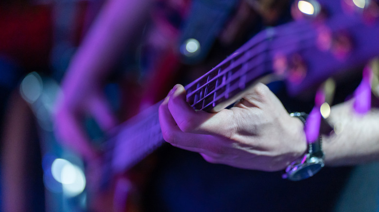 Photo man's hands playing an electric bass