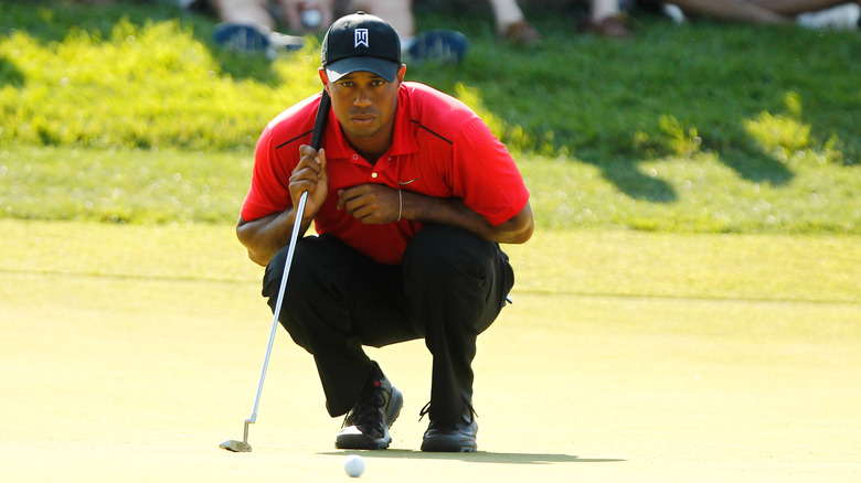 Tiger Woods crouching with gold club