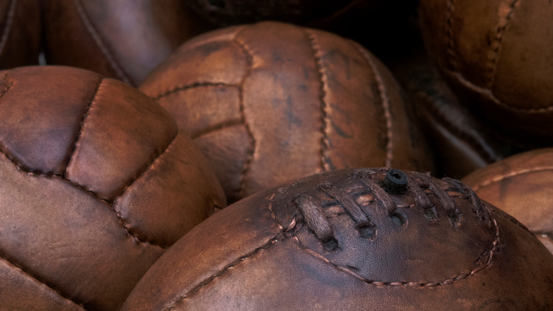 Old leather rugby balls in a bin