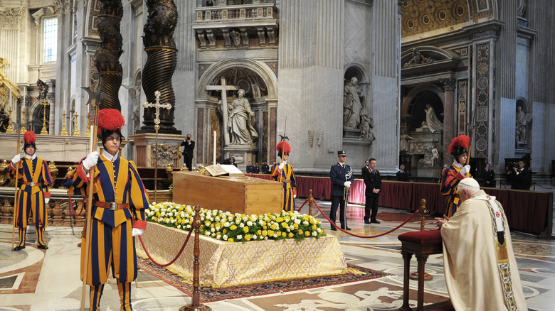 Pope Benedict kneeling before the casket of Pope John Paul