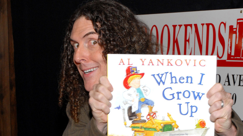 Weird Al Yankovic holding his children's book