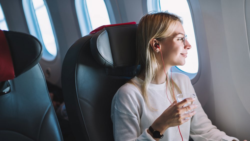 Woman drinking water while sitting on an airplane 