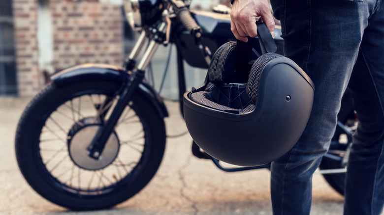 Motorcyclist with bike holding helmet