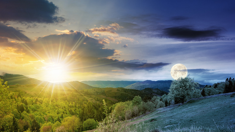 Sun and moon over hills and trees