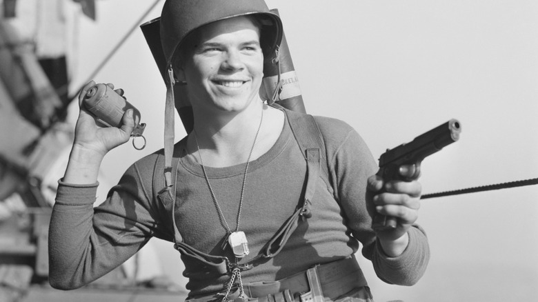 Army Ranger holding a grenade and gun while smiling