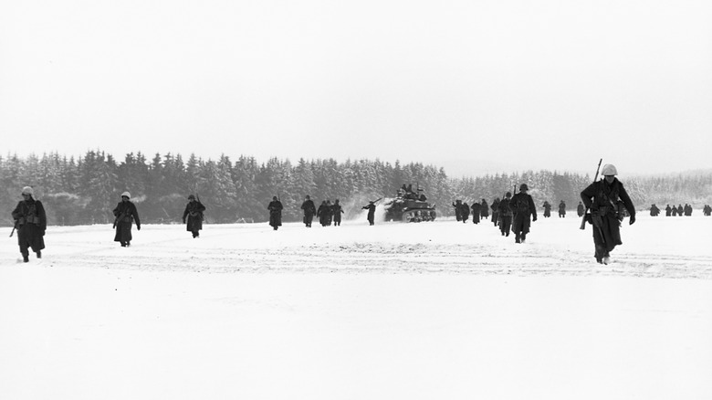 U.S. troops walking across a snowy field during the Battle of the Bulge