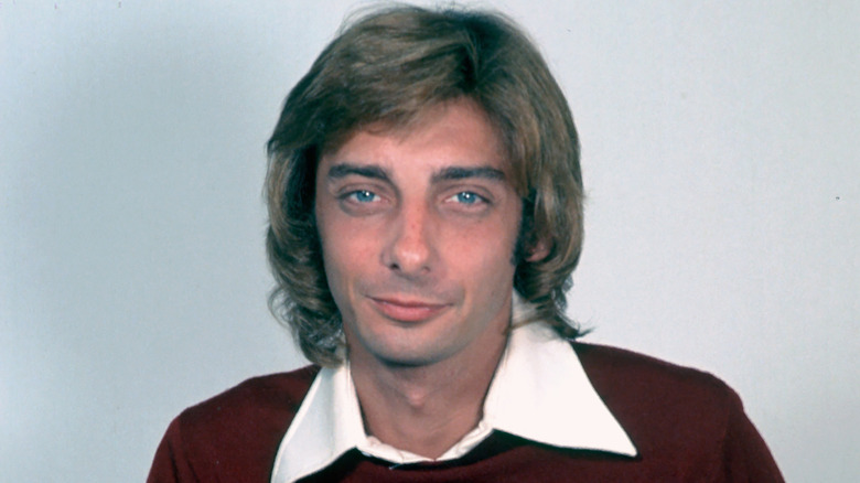 Barry Manilow posing in front of a grey background