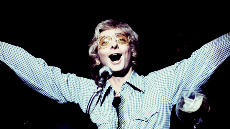 Barry Manilow singing on stage with arms raised