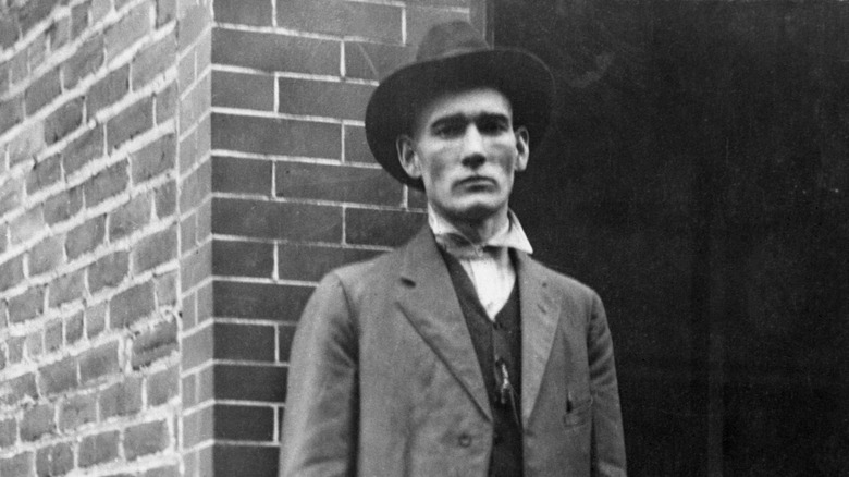 Matewan police chief Sid Hatfield standing against a brick building