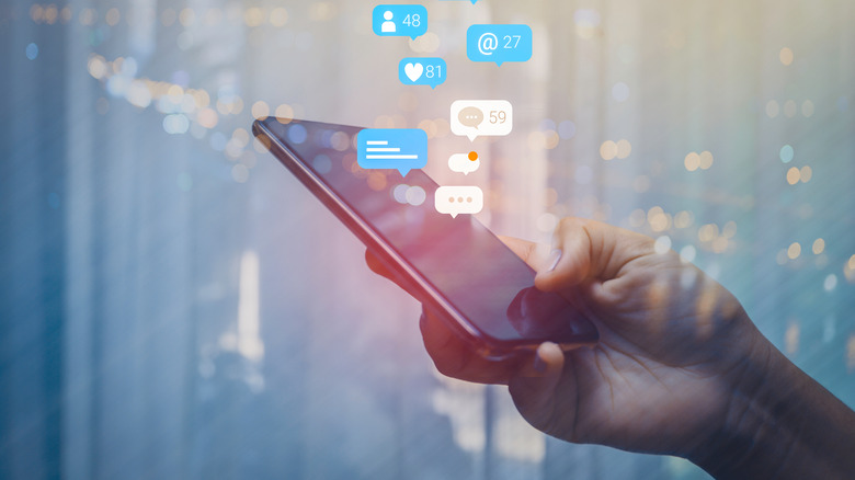 hand holding phone social media icons