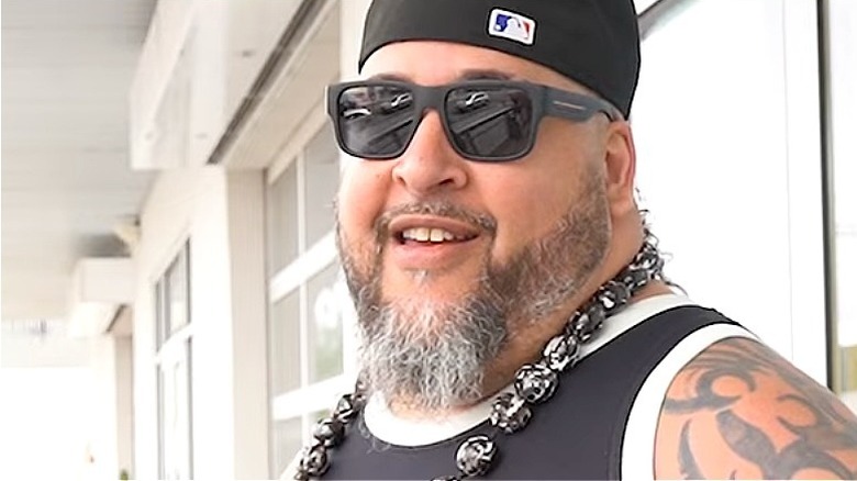 Manu smiling in dark sunglasses and black cap