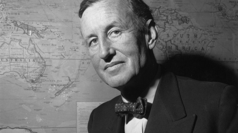 Ian Fleming sitting in front of a map on the wall