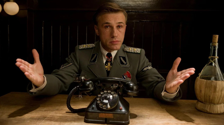 Christoph Waltz as Hans Landa gesturing before black phone