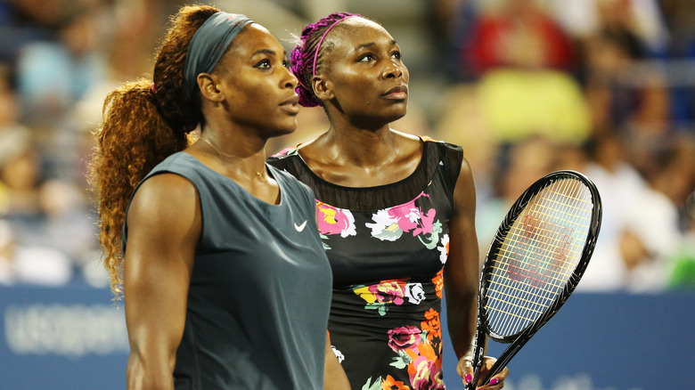 Venus and Serena Williams standing on tennis court