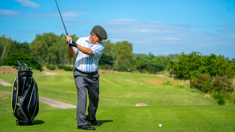 Golfer swinging to strike ball