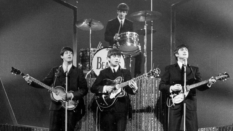 The Beatles in suits playing on stage